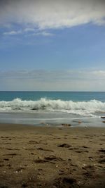 View of calm beach against cloudy sky