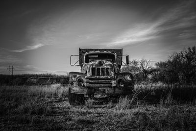 Abandoned pick-up truck on field against sky