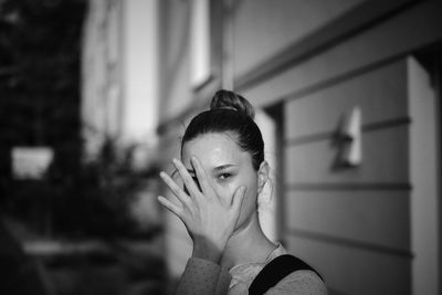 Portrait of woman shielding face against wall