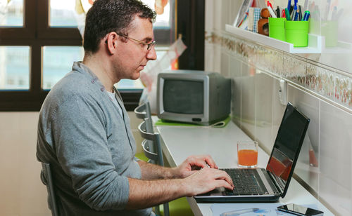 Side view of man using smart phone on table