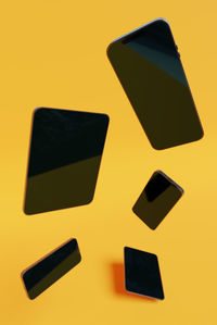 High angle view of mobile phone and smart phones on yellow background