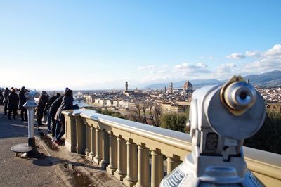 Close-up of hand-held telescope in city against blue sky