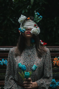 Woman looking at camera while standing against plants