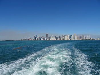 Scenic view of sea and buildings against clear blue sky