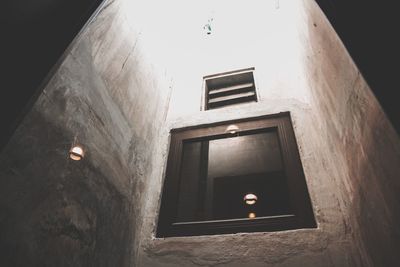 Low angle view of illuminated lamp on building wall