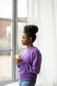 Thoughtful businesswoman with coffee cup looking through window