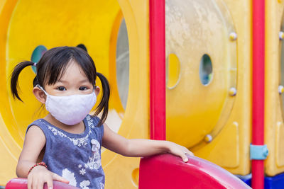 Portrait of girl wearing mask sitting on slide