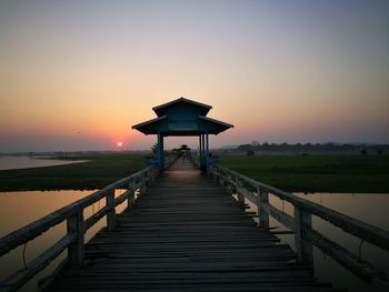 Pier over sea against clear sky during sunset