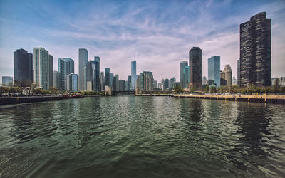 Sea by buildings against sky in city