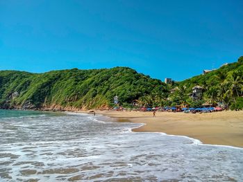 Scenic view of beach against clear blue sky