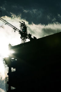 Low angle view of silhouette crane against sky at dusk