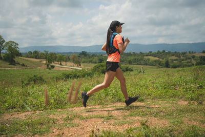 Full length of young woman exercising on field