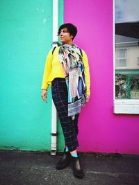 Full length of woman standing against wall