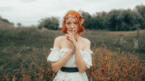 Portrait of young woman standing on field