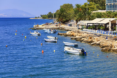 Boats moored in sea against blue sky