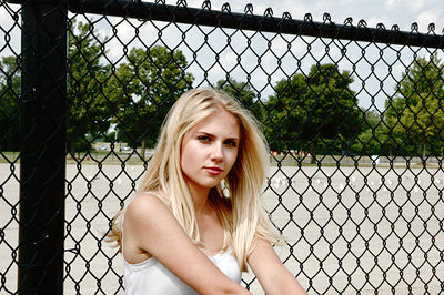 Portrait of a beautiful young woman in chainlink fence