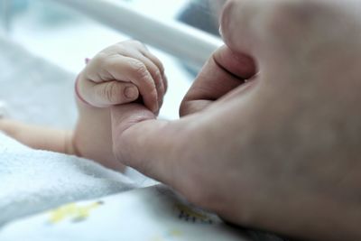 Close-up of baby holding finger of mother