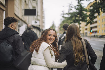 Portrait of smiling girl walking with teenage friends at street