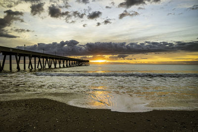 Bridge over sea against sky during sunset