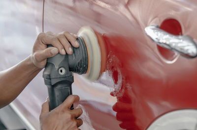 Cropped hands of man polishing car