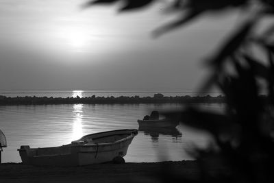 Boats moored on river against sky during sunset