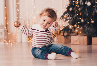 Boy playing with christmas ornaments on floor at home