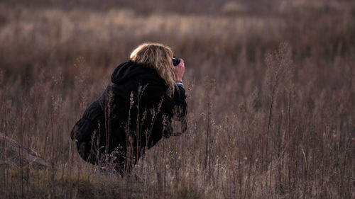 Woman crouching while photographing on field