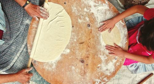 Directly above shot of mother and daughter rolling dough