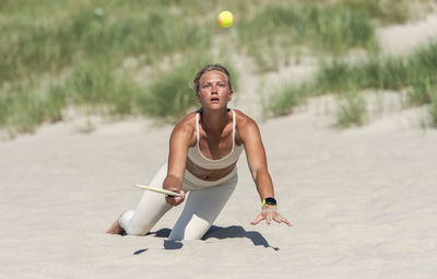 Young woman playing tennis on beach