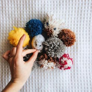 Cropped image of person feeding mouse by wool on table