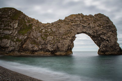 Rock formation by sea against sky