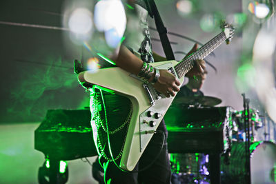 Midsection of musician playing guitar at concert