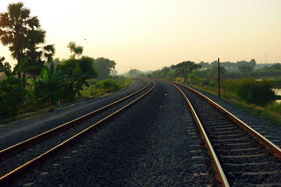 Railroad tracks by trees against clear sky