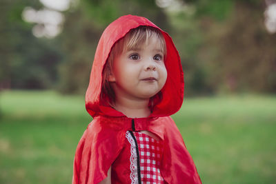 Charming baby in a red riding hood costume and golden retriever instead of a wolf