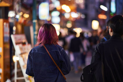 Rear view of women standing on street at night