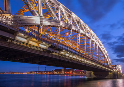 Low angle view of illuminated bridge over river against sky