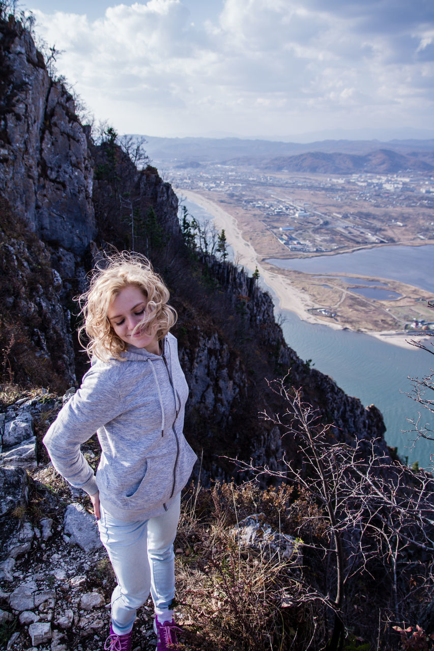 blond hair, one person, full length, standing, smiling, sky, real people, nature, casual clothing, leisure activity, day, looking at camera, outdoors, landscape, happiness, lifestyles, water, portrait, beauty in nature, childhood, tree, people