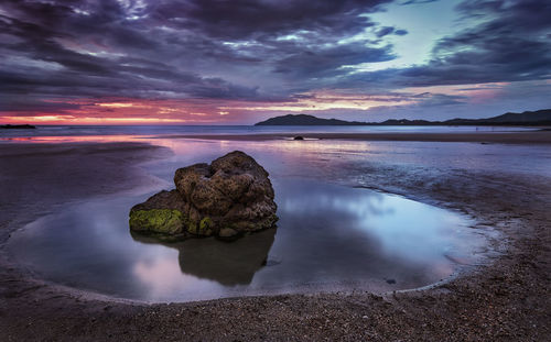 Scenic view of beach against dramatic sunset