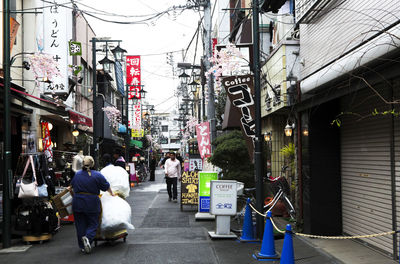 People walking on street amidst buildings in city