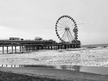 Ferris wheel by sea against sky