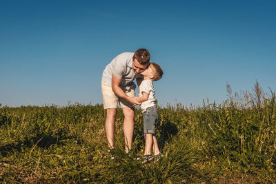 Full length of father with daughter on field against clear sky