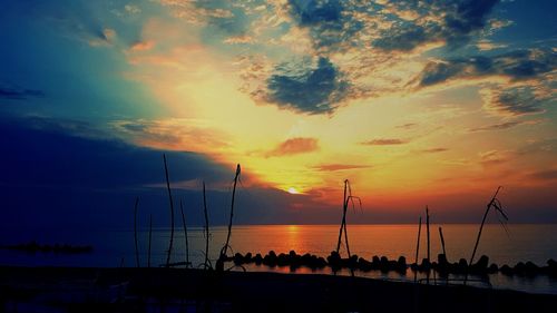 Silhouette sailboats on beach against sky during sunset