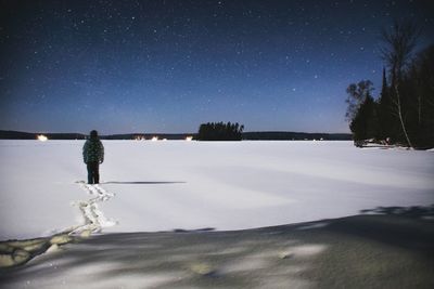 Man on frozen lake against sky at night