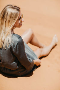 Side view of woman sitting on beach