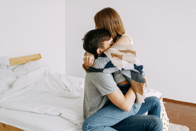 Rear view of mother and daughter sitting on sofa