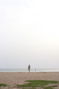 Man standing on beach against clear sky