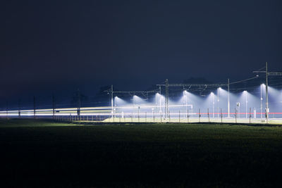 Illuminated field against clear sky at night