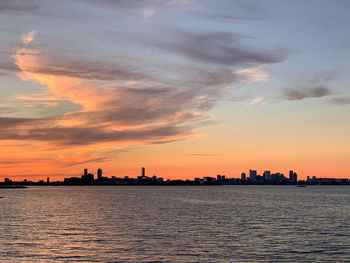 Scenic view of sea by buildings against sky during sunset, boston 