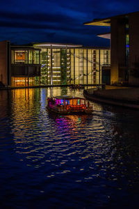 Illuminated bridge over river in city at night