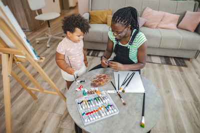 High angle view of mother and daughter sitting on sofa at home